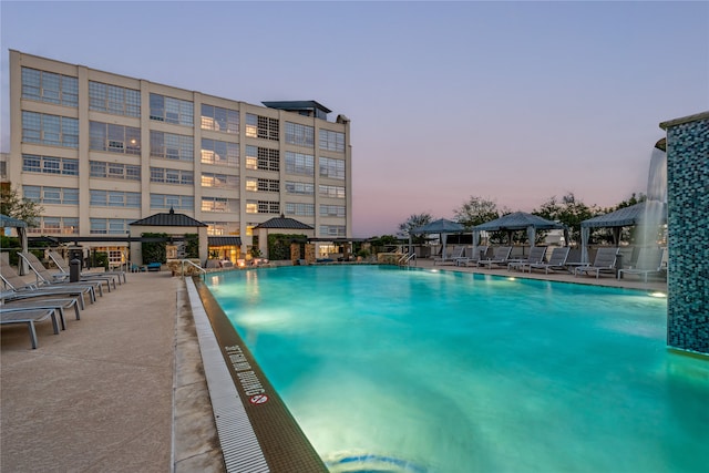 pool at dusk featuring a gazebo