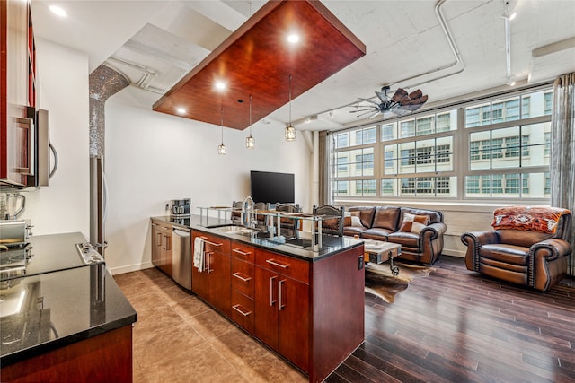 kitchen featuring ceiling fan, dishwasher, dark stone counters, sink, and pendant lighting