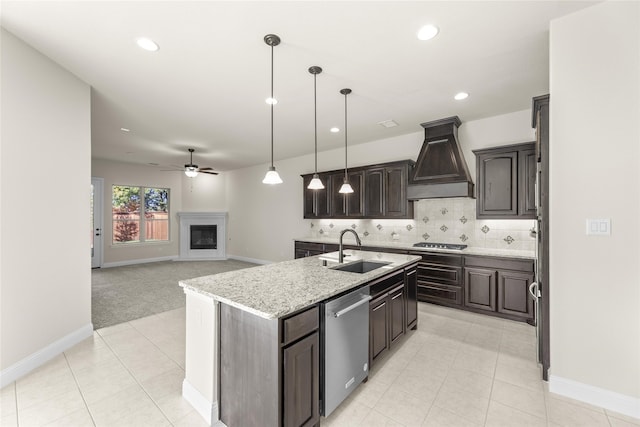 kitchen featuring custom exhaust hood, a center island with sink, sink, ceiling fan, and appliances with stainless steel finishes