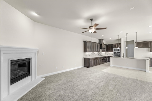 unfurnished living room featuring ceiling fan, sink, and light carpet