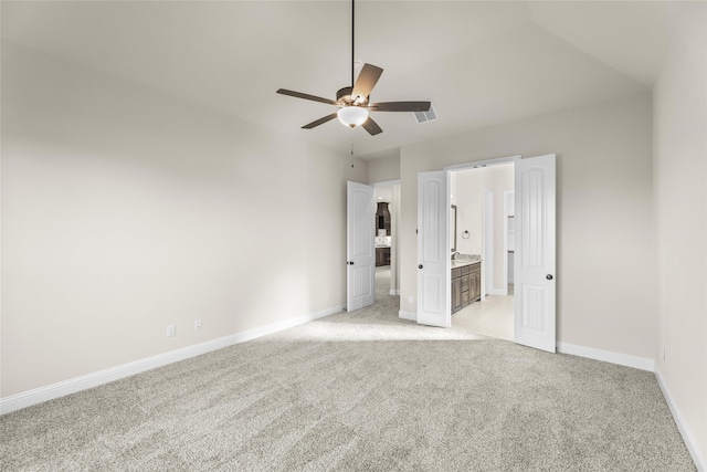 unfurnished bedroom featuring ceiling fan, light colored carpet, and ensuite bath