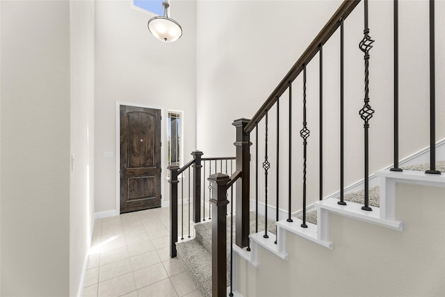 foyer entrance featuring light tile patterned floors and a towering ceiling