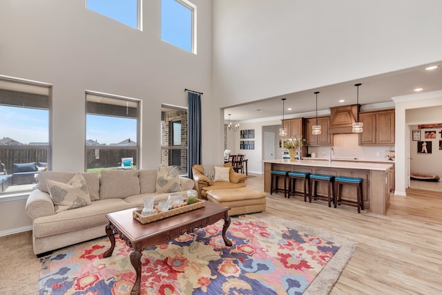 living room with a chandelier, a high ceiling, and light hardwood / wood-style floors