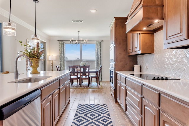 kitchen with appliances with stainless steel finishes, premium range hood, crown molding, sink, and pendant lighting