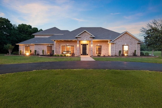 view of front of home with a shingled roof and a yard