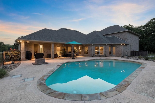 pool at dusk featuring a fenced in pool, a patio, and fence