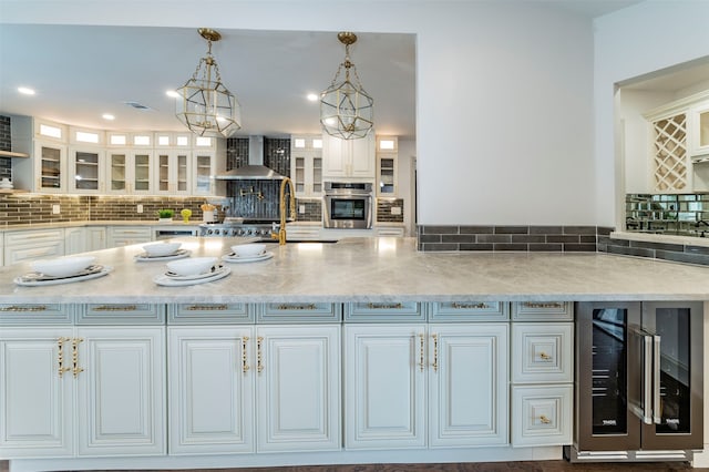 kitchen featuring oven, decorative light fixtures, beverage cooler, wall chimney range hood, and tasteful backsplash