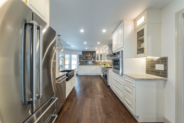 kitchen with white cabinets, sink, backsplash, high end appliances, and dark hardwood / wood-style floors