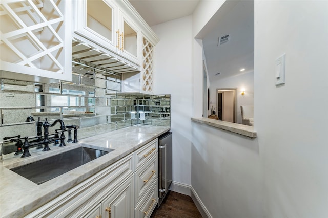 kitchen with light stone countertops, dark hardwood / wood-style flooring, white cabinetry, sink, and tasteful backsplash