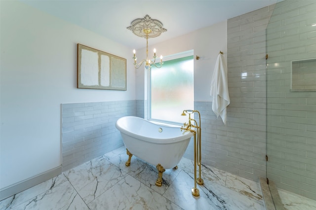 bathroom with tile walls, a notable chandelier, a bathing tub, and tile flooring