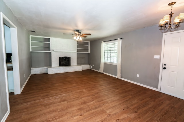 unfurnished living room with brick wall, a fireplace, ceiling fan with notable chandelier, and wood-type flooring