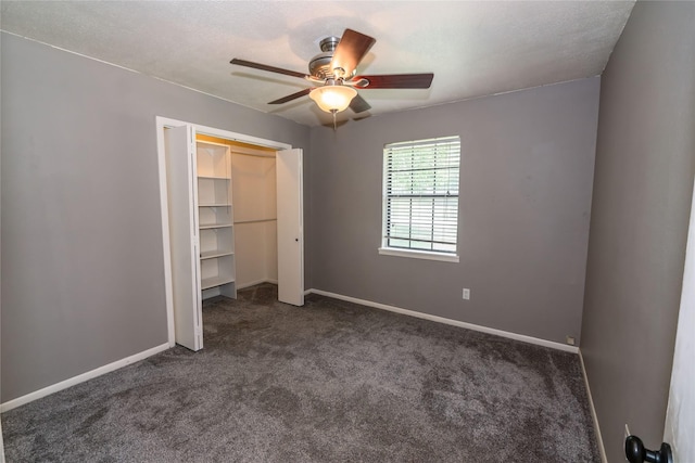 unfurnished bedroom with a textured ceiling, a closet, dark carpet, and baseboards