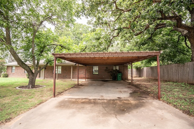 view of car parking with concrete driveway, a carport, and fence