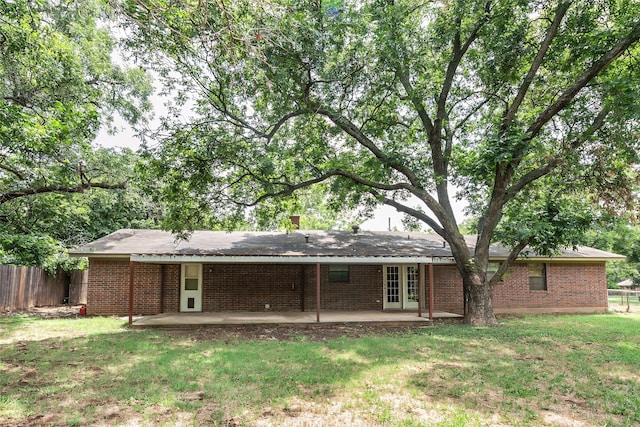 rear view of house with a patio, brick siding, a lawn, and fence