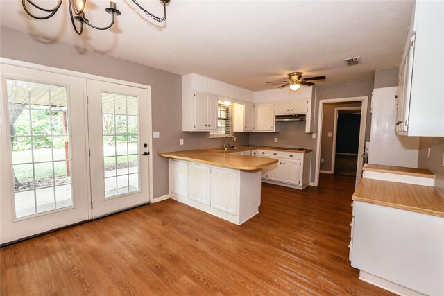 kitchen with white cabinets, light hardwood / wood-style floors, sink, and kitchen peninsula