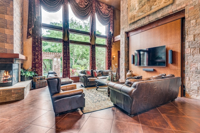 living room featuring a stone fireplace, tile flooring, and a towering ceiling