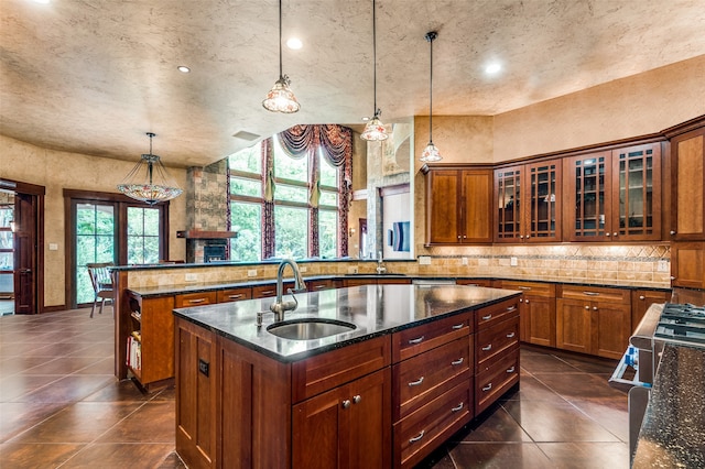 kitchen featuring sink, pendant lighting, dark tile flooring, and a center island with sink