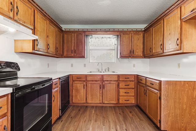 kitchen with a textured ceiling, wood-type flooring, black appliances, and sink