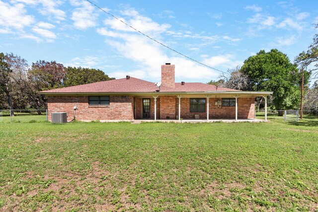 rear view of property with central air condition unit and a lawn