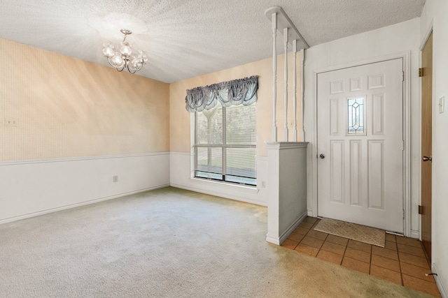 entrance foyer featuring a textured ceiling, light tile floors, and an inviting chandelier