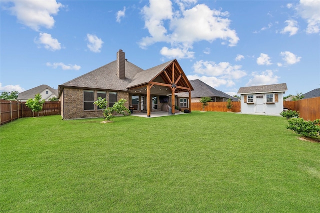 rear view of property with a patio area, a yard, and an outdoor structure