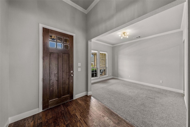 foyer entrance featuring crown molding and dark colored carpet