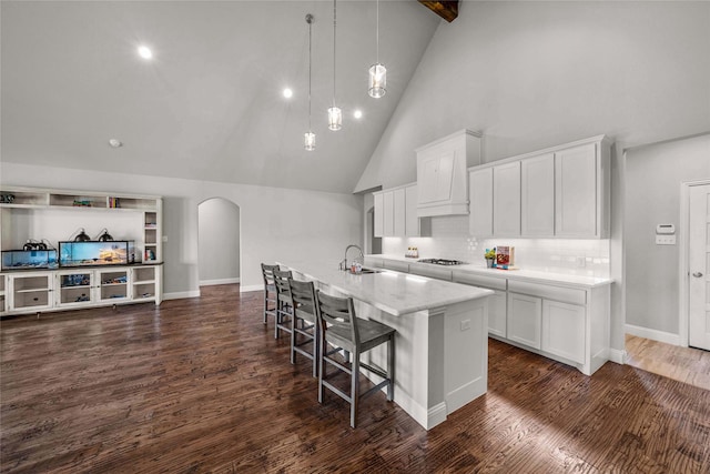 kitchen featuring sink, white cabinets, decorative light fixtures, and a kitchen island with sink