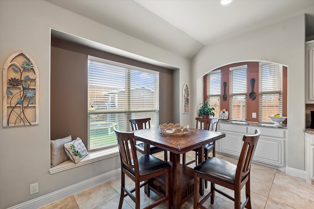 dining space with lofted ceiling, a wealth of natural light, and light tile patterned floors