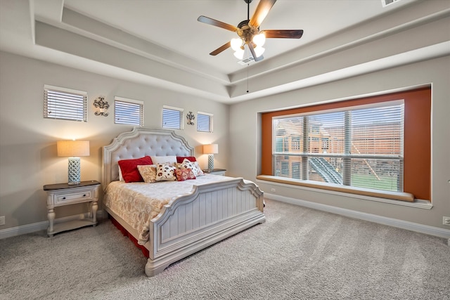 bedroom with multiple windows, ceiling fan, and a tray ceiling