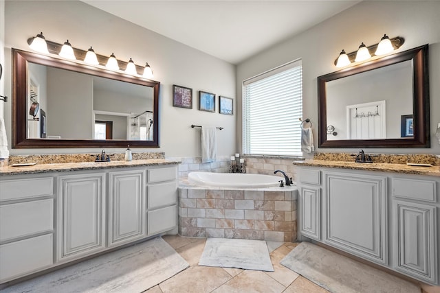 bathroom featuring tiled tub, vanity, and tile patterned floors