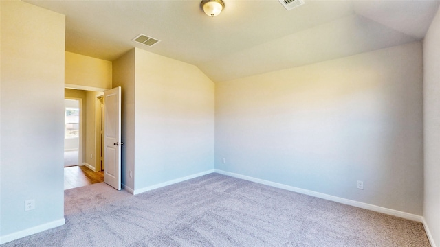 carpeted spare room featuring lofted ceiling