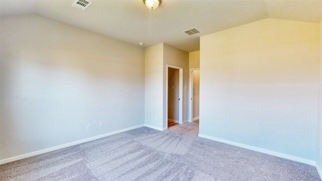 spare room with carpet floors and vaulted ceiling