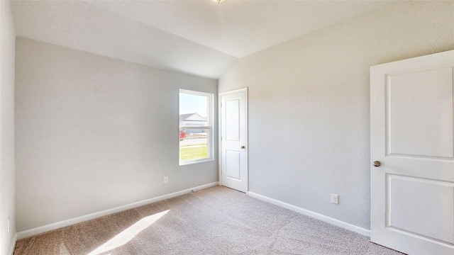 unfurnished room featuring lofted ceiling and light colored carpet