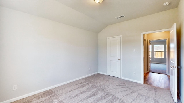 unfurnished bedroom featuring vaulted ceiling and light carpet