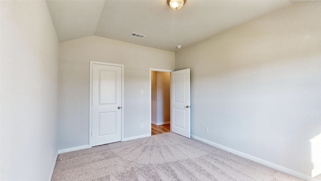 unfurnished bedroom featuring light carpet and vaulted ceiling