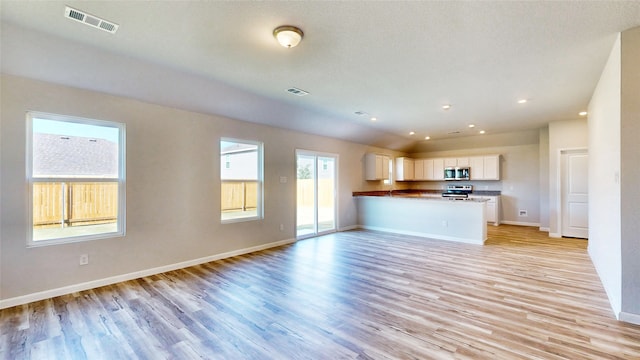 unfurnished living room with a textured ceiling and light hardwood / wood-style flooring