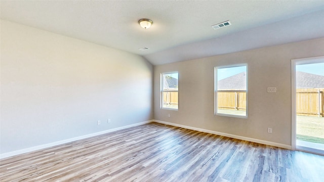 spare room featuring light hardwood / wood-style floors and vaulted ceiling