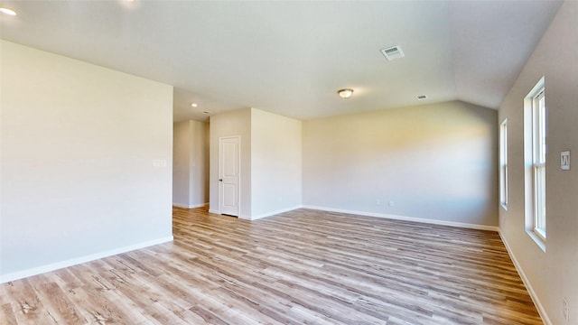 spare room with light hardwood / wood-style floors and vaulted ceiling