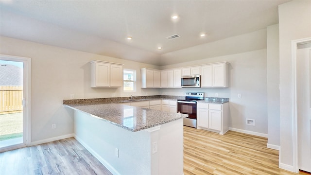 kitchen with appliances with stainless steel finishes, kitchen peninsula, white cabinetry, and light hardwood / wood-style flooring