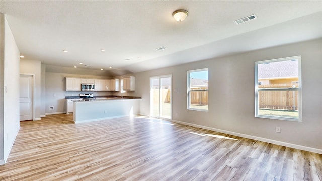 unfurnished living room featuring plenty of natural light and light hardwood / wood-style flooring