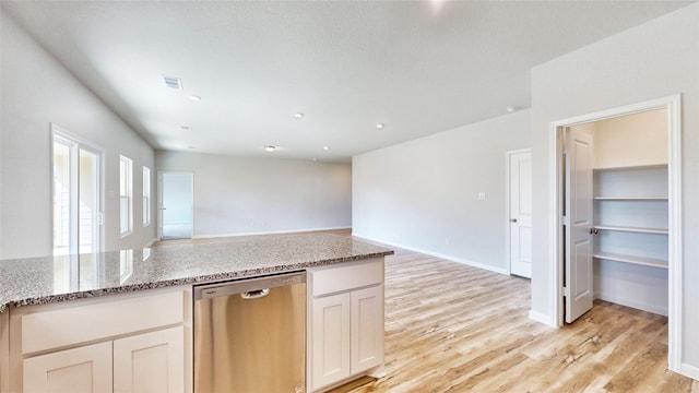 kitchen with light stone countertops, stainless steel dishwasher, light hardwood / wood-style floors, and white cabinets