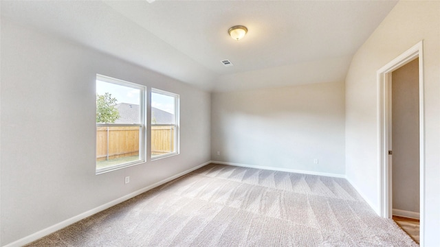 carpeted spare room with vaulted ceiling