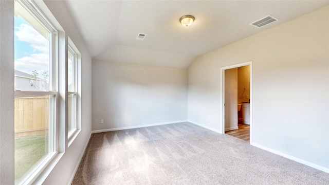 spare room featuring light carpet and lofted ceiling