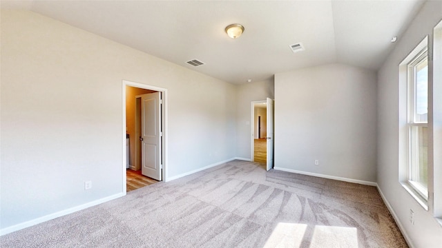 carpeted spare room with vaulted ceiling