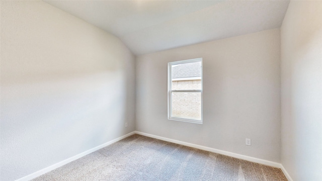 carpeted empty room featuring lofted ceiling