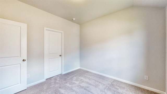 unfurnished room featuring lofted ceiling and light colored carpet