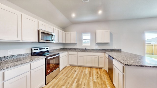 kitchen featuring lofted ceiling, white cabinets, appliances with stainless steel finishes, and a wealth of natural light