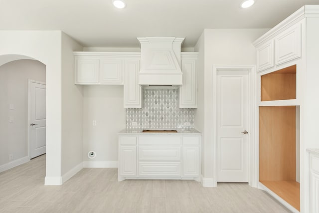 kitchen featuring arched walkways, light countertops, white cabinetry, and decorative backsplash