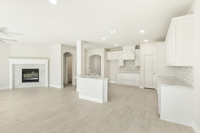 kitchen featuring a sink, a ceiling fan, white cabinets, open floor plan, and backsplash