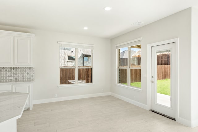 unfurnished dining area with light wood finished floors, recessed lighting, and baseboards